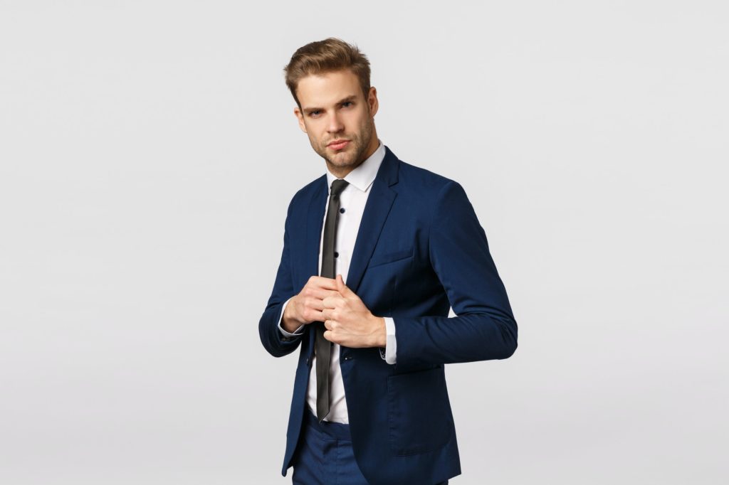 Determined, confident businessman in suit, fixing jacket, looking sassy and pleased camera, signed